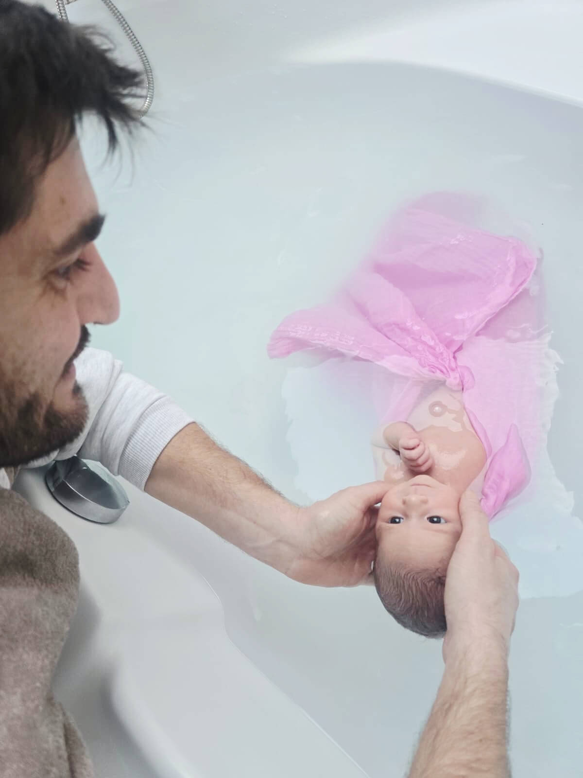 Un papa donnant le bain à son bébé